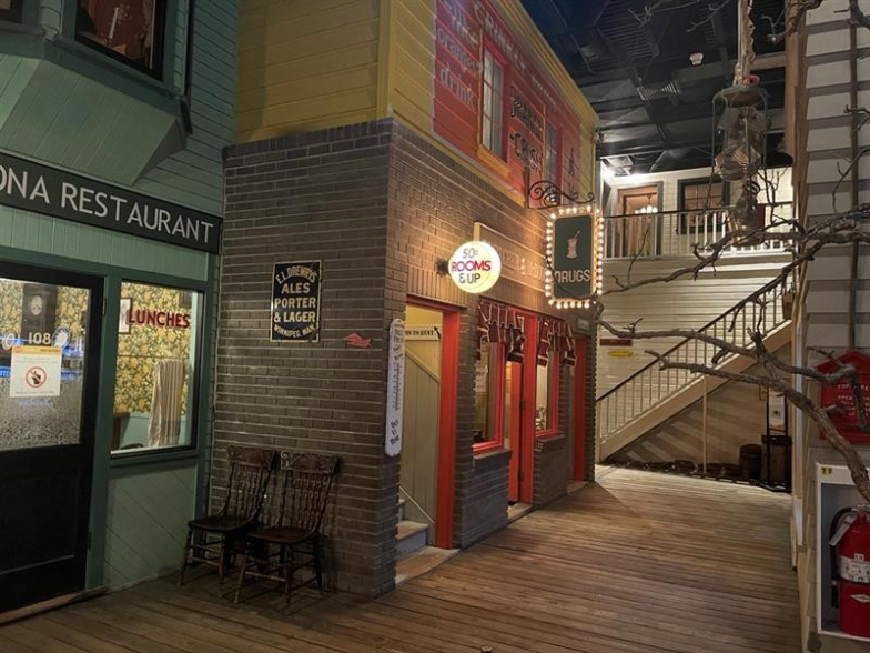 Shows a small town like setup with store fronts, the buildings have different colours and use a variety of materials such as wood and brick