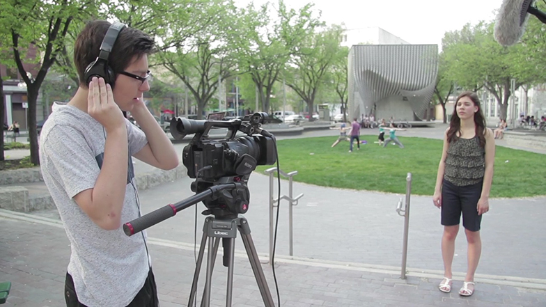 A person has a camera and is filming another person in a park in summer