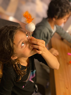 A student tries balancing a ball on her nose
